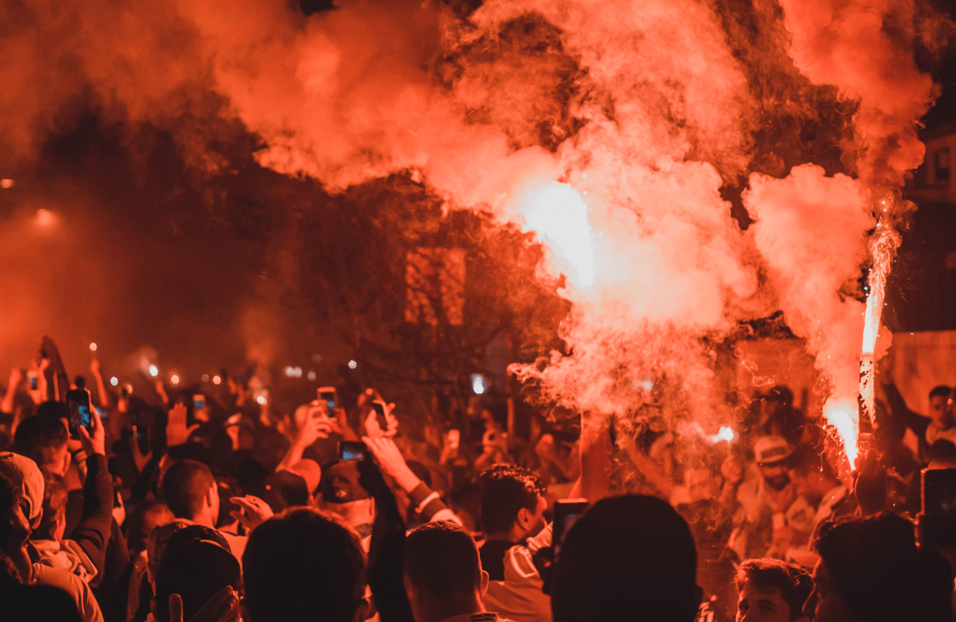Protesters gather in the street with red flares lit